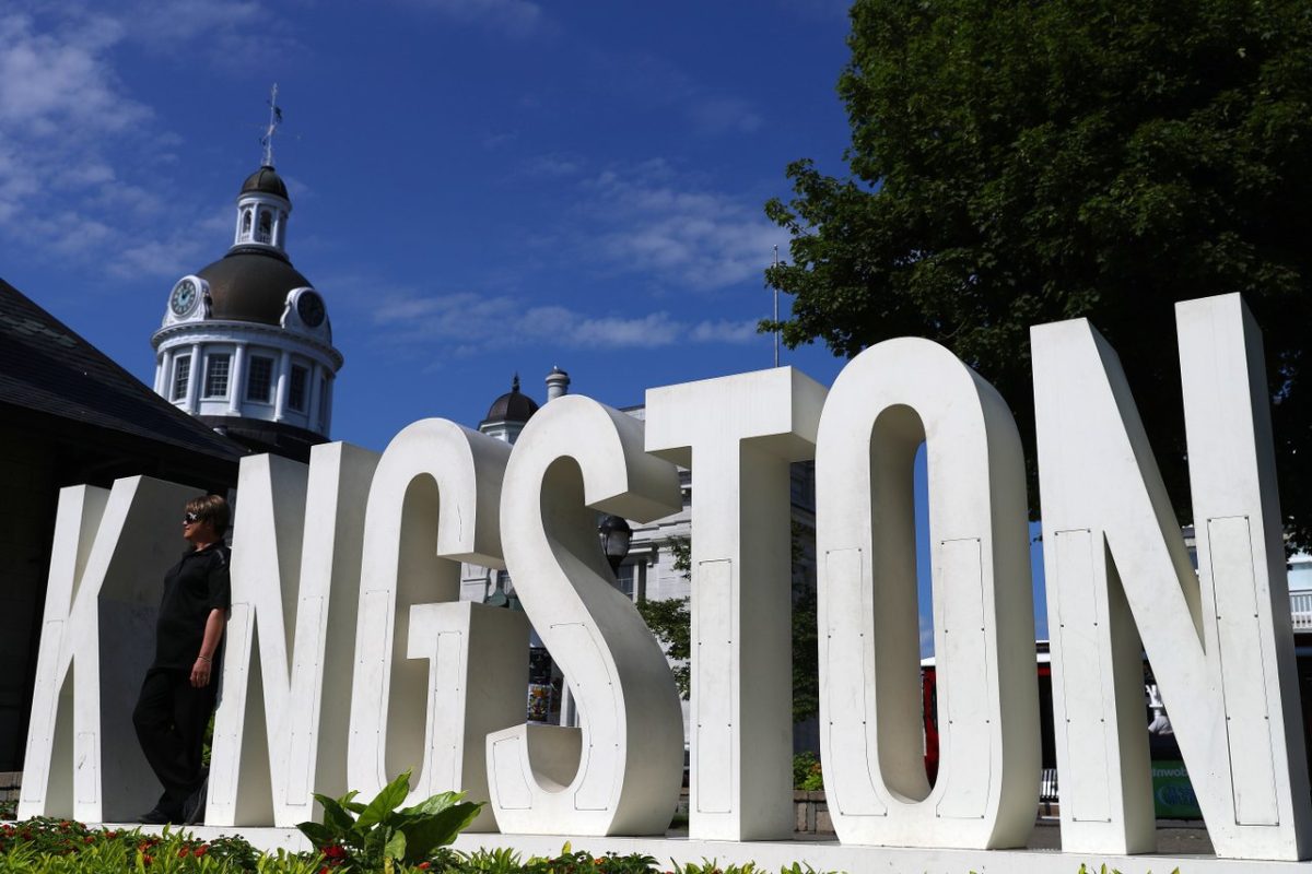 A large outdoor signage installation with white letters reading "KINGSTON" in all caps, located in downtown Kingston, Ontario.